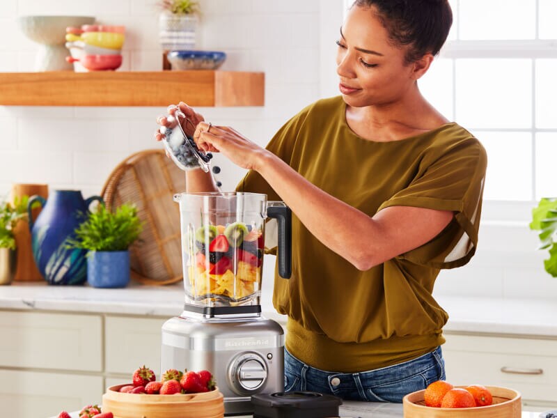 Person adding fresh fruit to a KitchenAid® blender