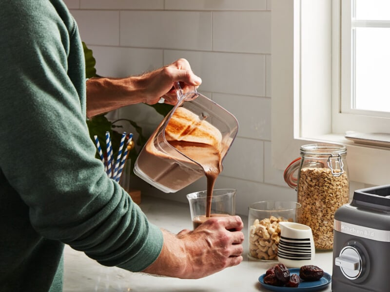 Person pouring a blended drink into a glass