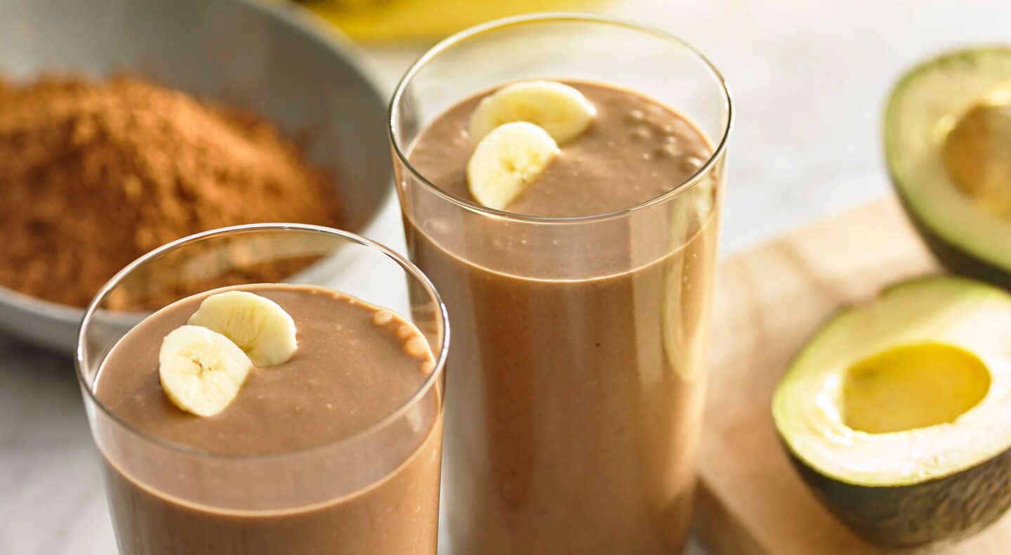 Glasses filled with blended chocolate drinks topped with fresh fruit Glasses filled with chocolate smoothie and topped with banana slices