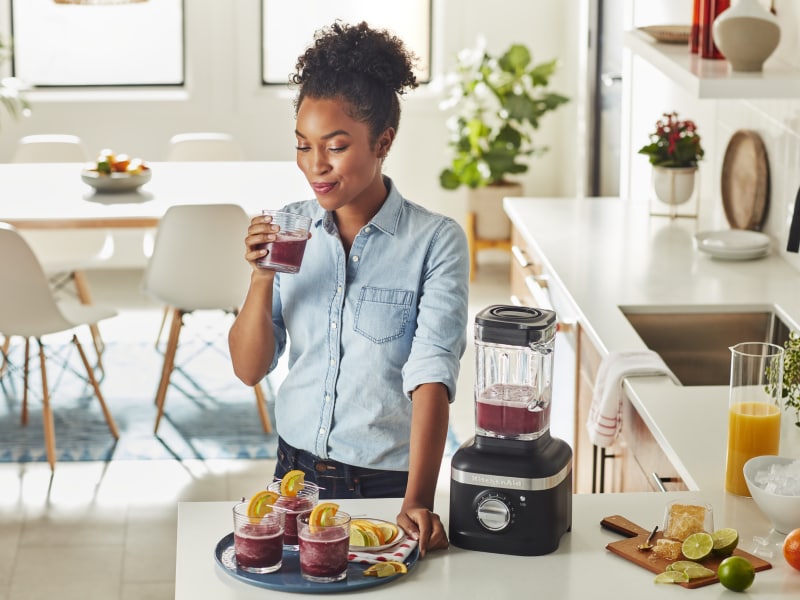 Person with a tray of cocktails, sipping from a glass Person with a tray of cocktails, sipping from a glass