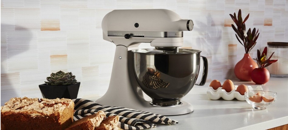 A white KitchenAid® stand mixer beside sliced loaf cake and eggs A white KitchenAid® stand mixer beside sliced loaf cake and eggs