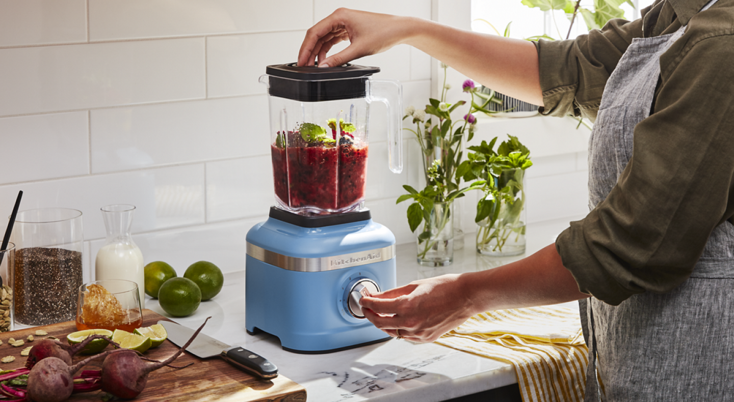 Woman with a KitchenAid® blender blending mixture in a modern kitchen Woman with a KitchenAid® blender blending mixture in a modern kitchen
