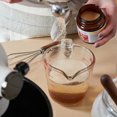 Someone mixing yeast with water in a measuring glass