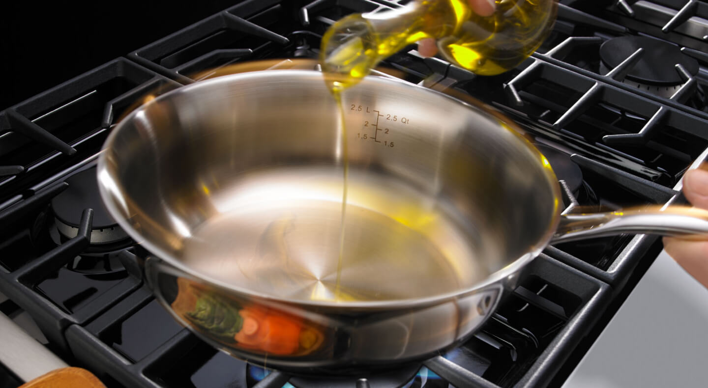 Person pouring oil in a pan Person pouring oil in a pan