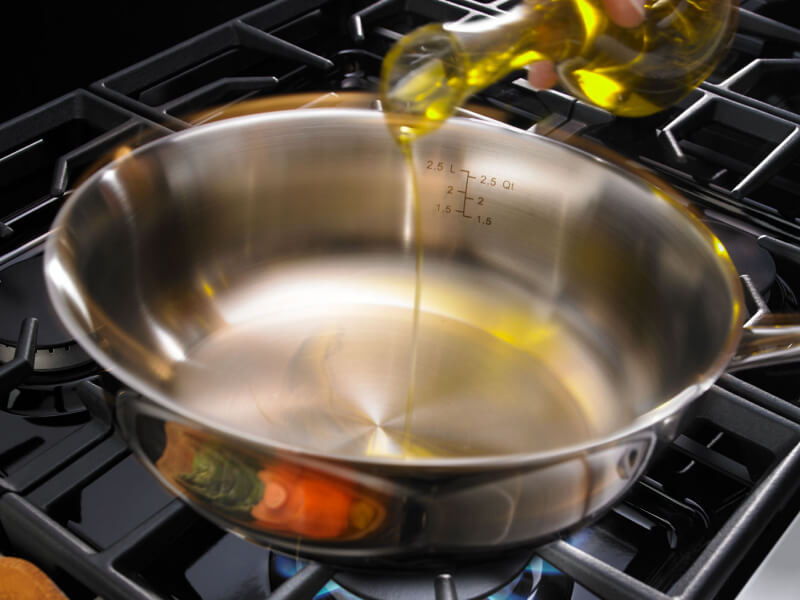 Person pouring oil in a pan Person pouring oil in a pan