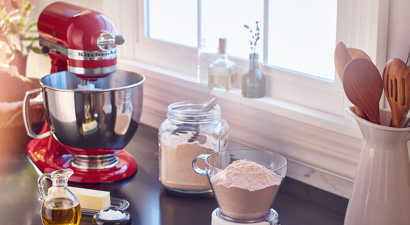 Red KitchenAid® stand mixer on countertop with baking ingredients Red KitchenAid® stand mixer on countertop with baking ingredients