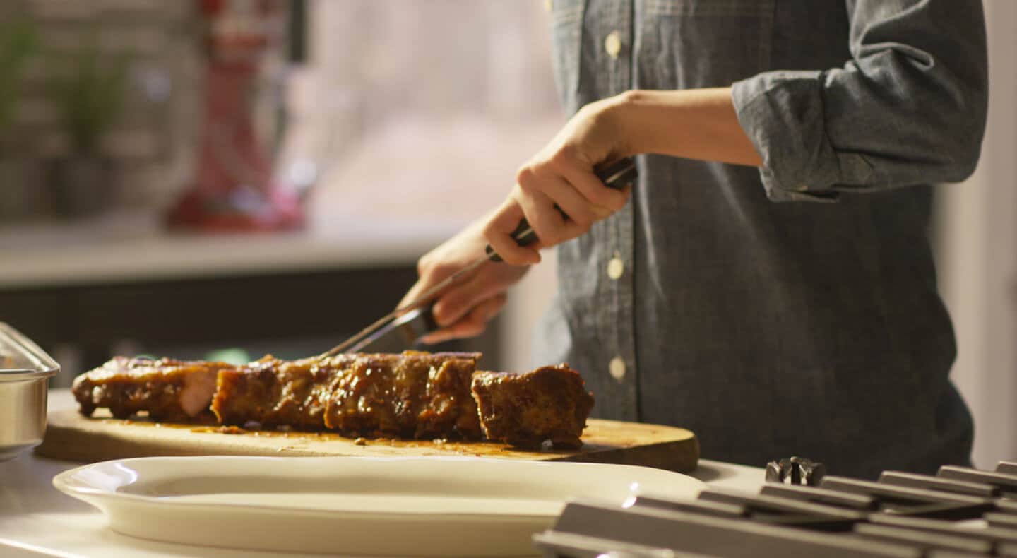 Cook cutting into a tender rack of ribs. Cook cutting into a tender rack of ribs.