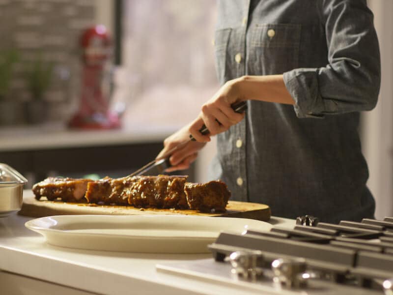 Cook cutting into a tender rack of ribs. Cook cutting into a tender rack of ribs.