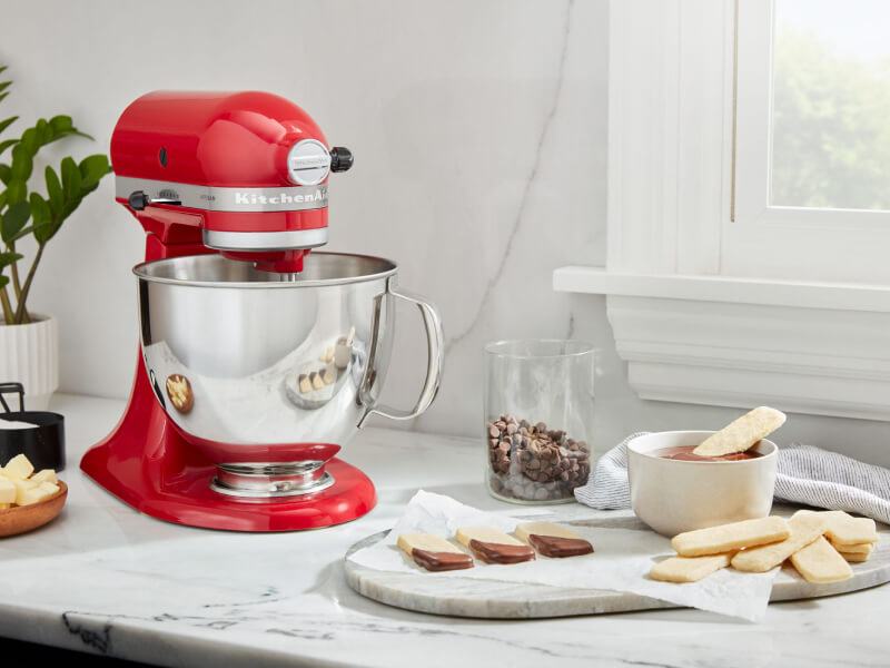 A red KitchenAid® stand mixer and a prepared dessert on a countertop A red KitchenAid® stand mixer and a prepared dessert on a countertop