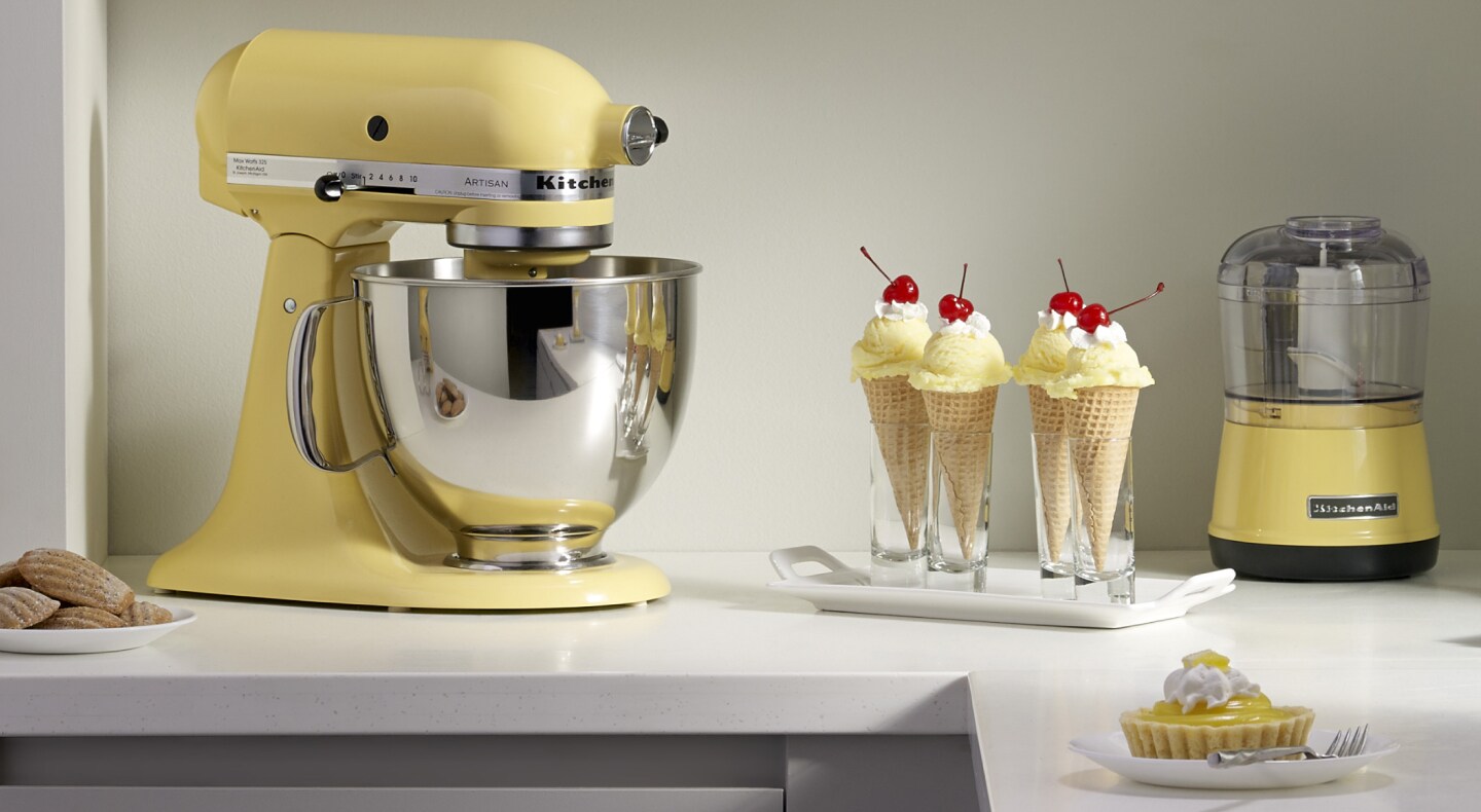 A yellow KitchenAid® stand mixer next to ice cream in waffle cones A yellow KitchenAid® stand mixer next to ice cream in waffle cones