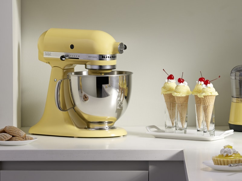 A yellow KitchenAid® stand mixer next to ice cream in waffle cones A yellow KitchenAid® stand mixer next to ice cream in waffle cones