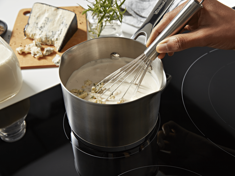 A person whisking a pot of vegan queso. A person whisking a pot of vegan queso.
