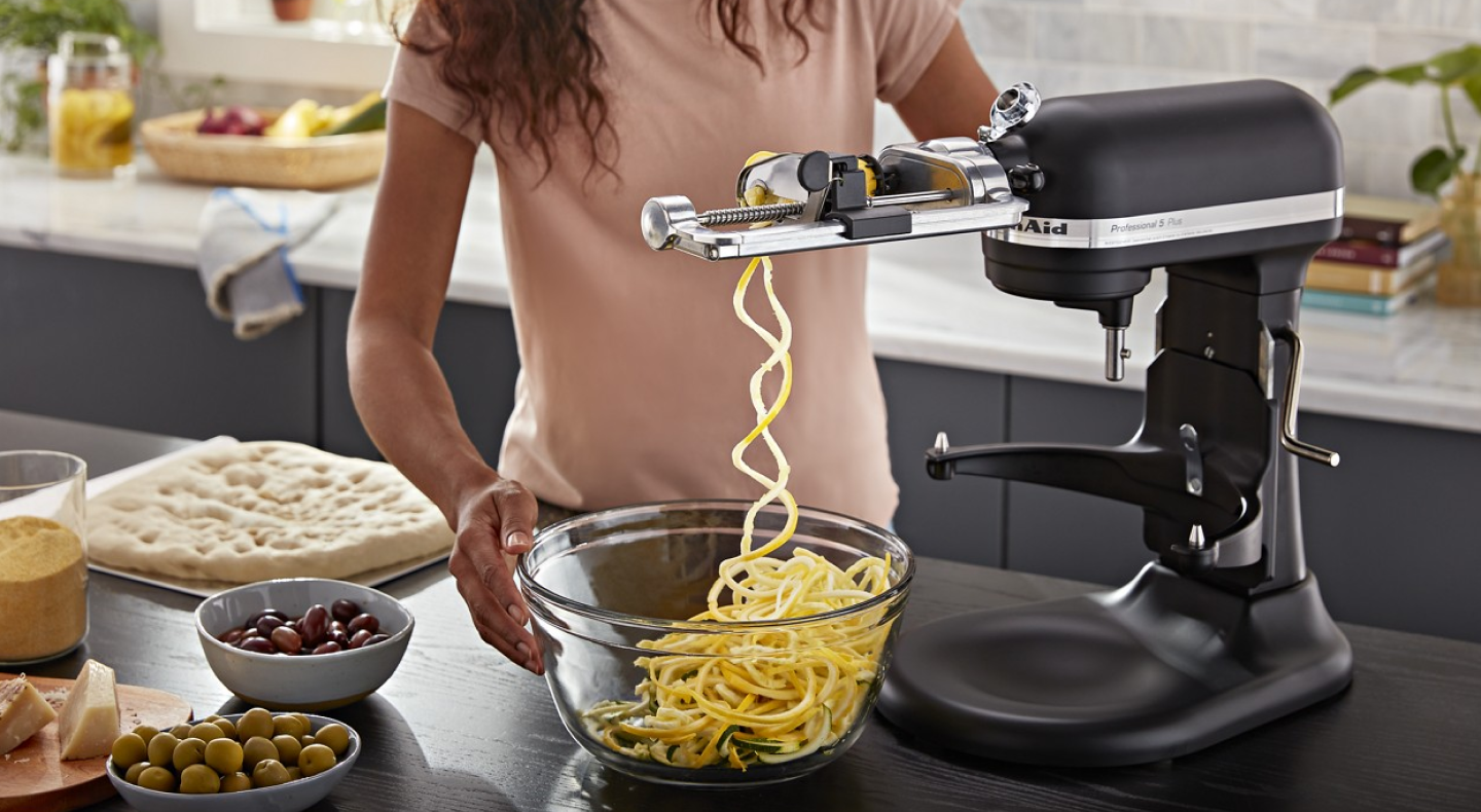 Same as Image Alt Text Woman creating veggie noodles with KitchenAid® mixer and spiralizer attachment