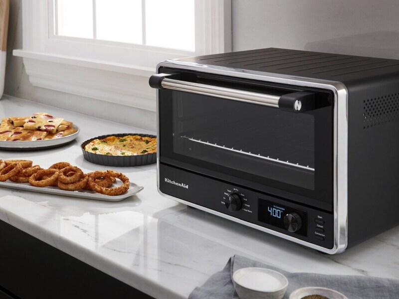 Black KitchenAid brand countertop oven on granite countertop next to finished dishes