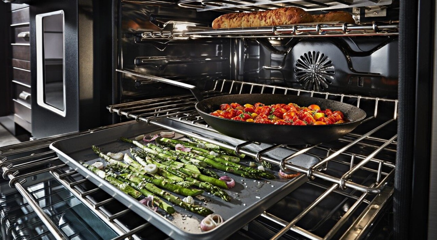 Asparagus, vegetables and bread cooking on separate racks in the oven Asparagus, vegetables and bread cooking on separate racks in the oven