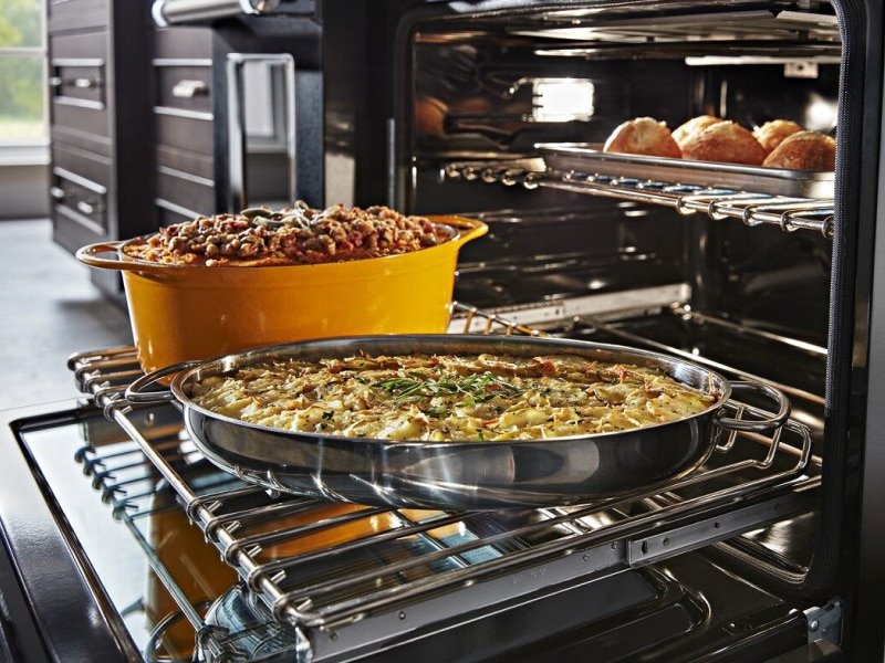 Casseroles sitting on top of an extended bottom oven rack with a dish cooking above Casseroles sitting on top of an extended bottom oven rack with a dish cooking above