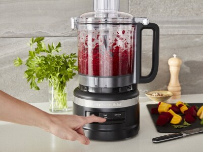 Woman mincing ingredients in a KitchenAid® food processor.