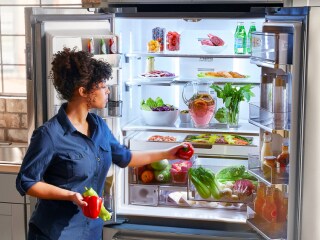 Person placing food inside a French door refrigerator