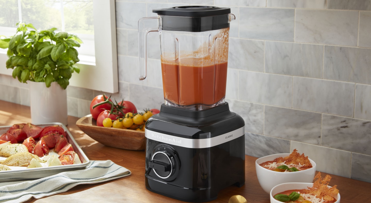 KitchenAid® blender filled with puree next to various ingredients KitchenAid® blender filled with puree next to various ingredients