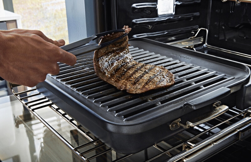 Hand lifting a cut of steak off of a rack Hand lifting a cut of steak off of a rack