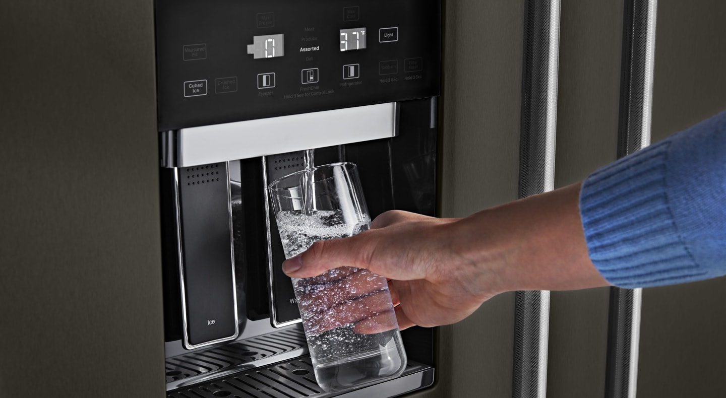 Person filling water from refrigerator dispenser Person filling water from refrigerator dispenser