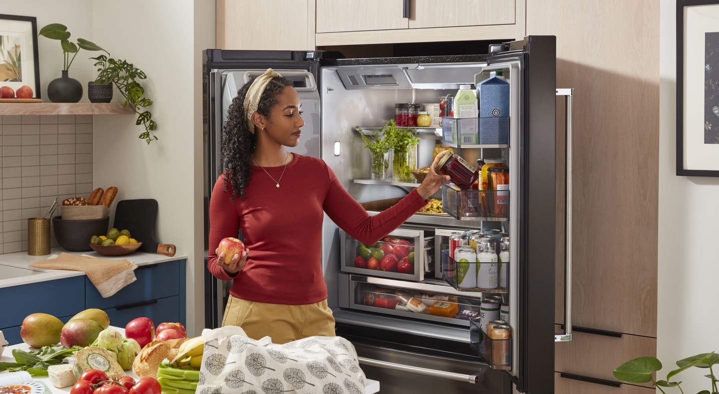 Person removing items from the door of a refrigerator Person removing items from the door of a refrigerator