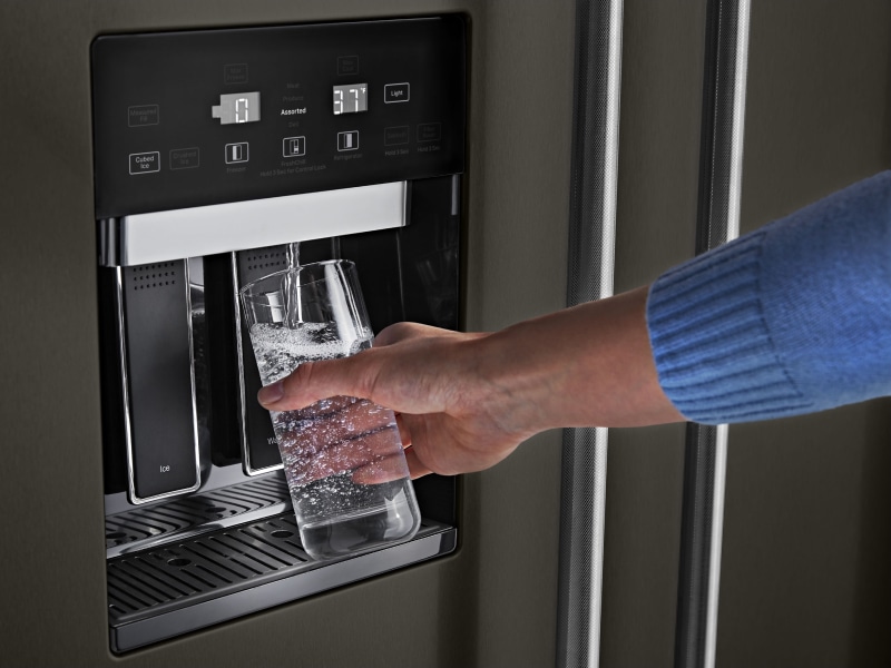 Person filling water from refrigerator dispenser Person filling water from refrigerator dispenser