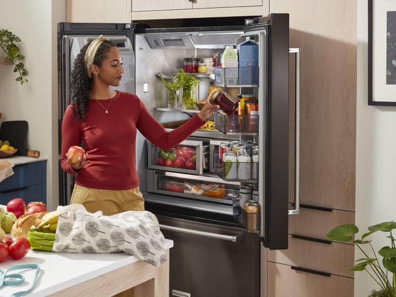 Person removing items from the door of a refrigerator Person removing items from the door of a refrigerator