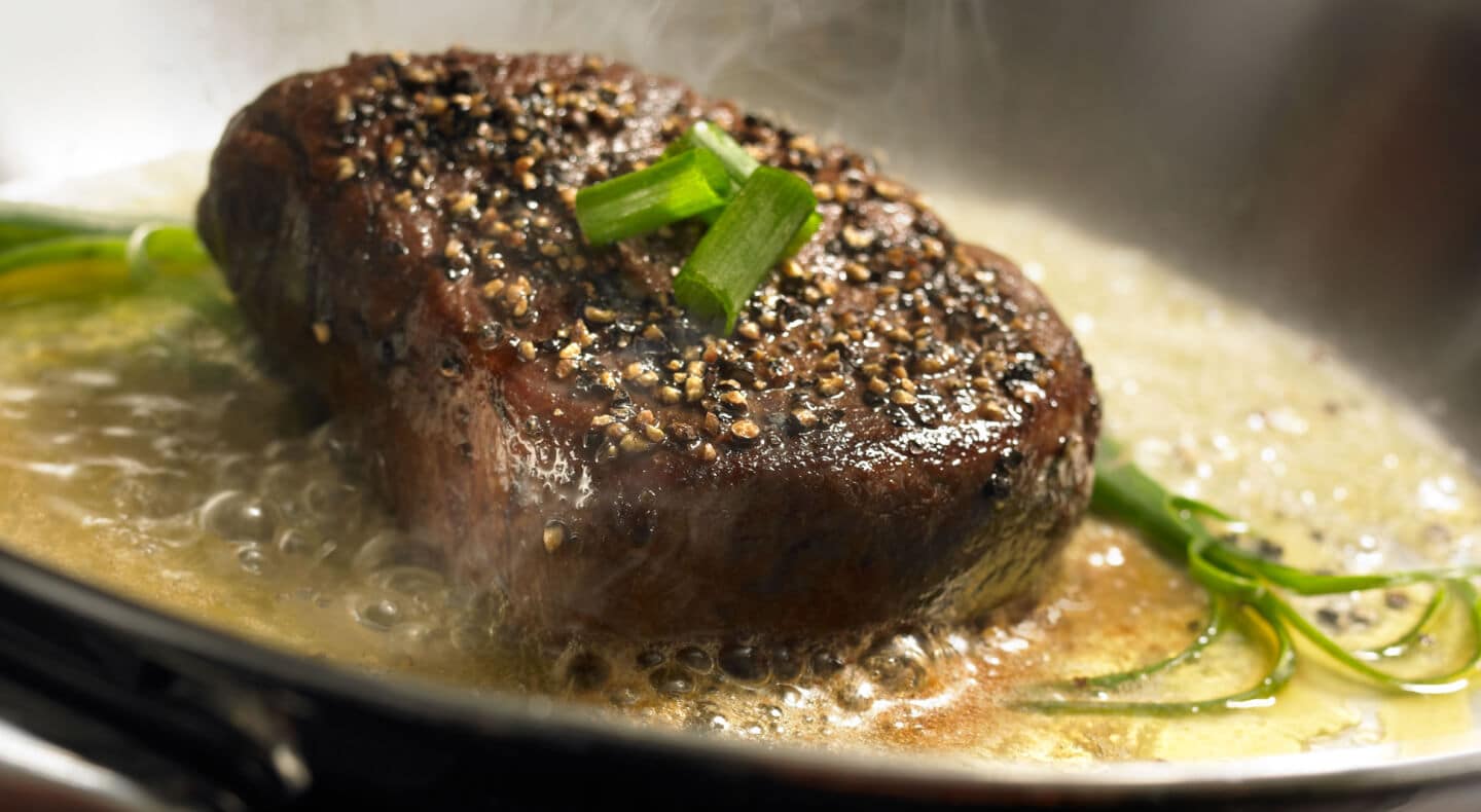 Cooked steak topped with green onions Cooked steak topped with green onions