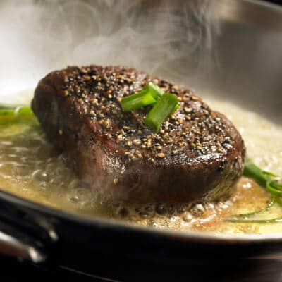 Cooked steak topped with green onions Cooked steak topped with green onions