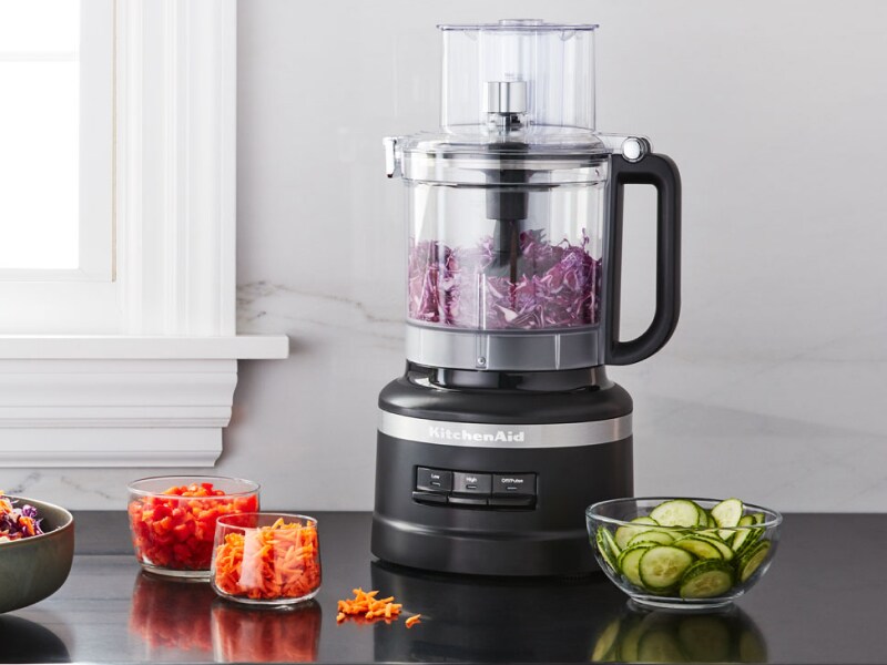 Salad topped with shredded carrots next to a black KitchenAid® food processor Salad topped with shredded carrots next to a black KitchenAid® food processor