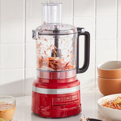 Carrots shredding inside a red KitchenAid® food processor