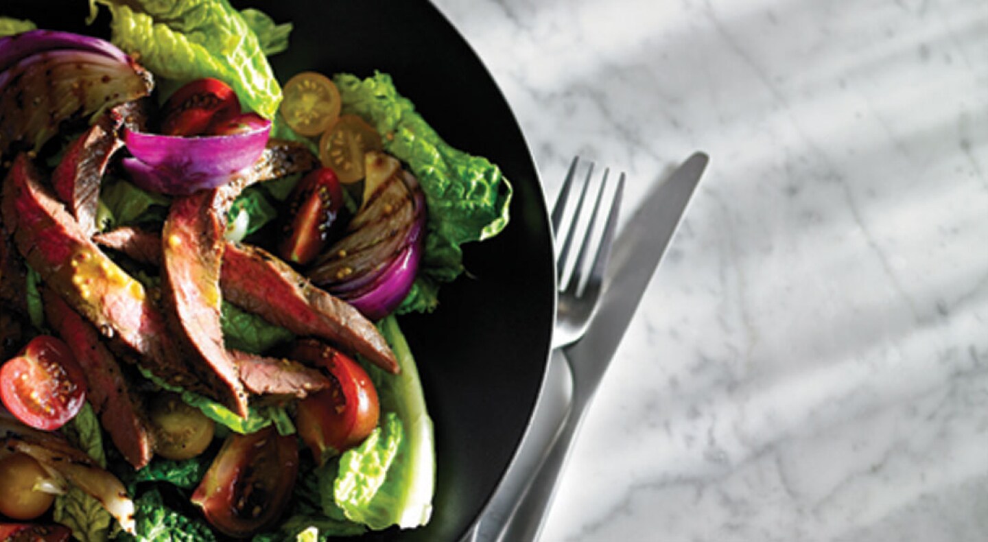 Close-up of tossed salad with steak and sliced tomatoes