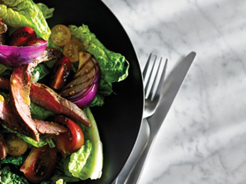 Close-up of tossed salad with steak and sliced tomatoes
