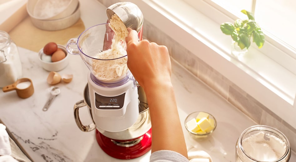 Hand pouring flour into a sifting attachment on a stand mixer Hand pouring flour into a sifting attachment on a stand mixer