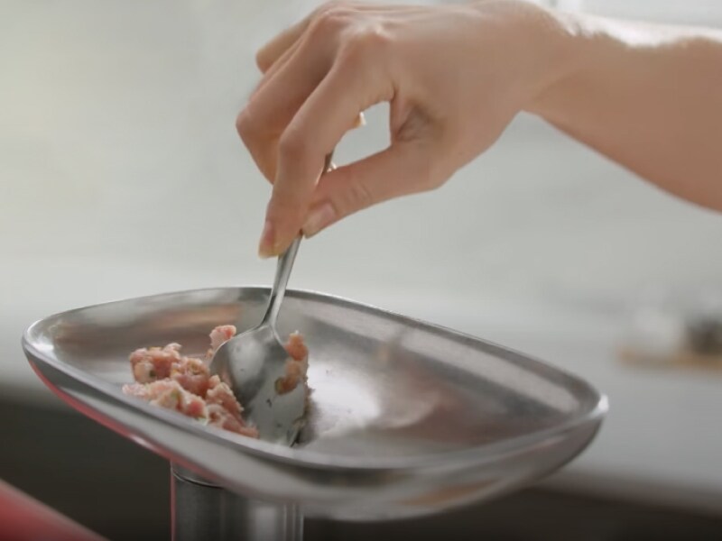 Person feeding meat into a grinder