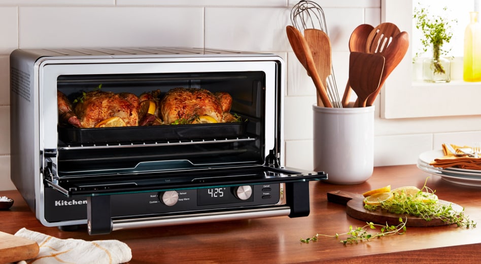 Two whole roasted chickens and greens cooked inside a KitchenAid® countertop oven Two whole roasted chickens and greens cooked inside a KitchenAid® countertop oven