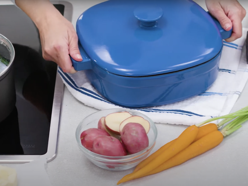 Person holding handles of dutch oven Person holding handles of dutch oven