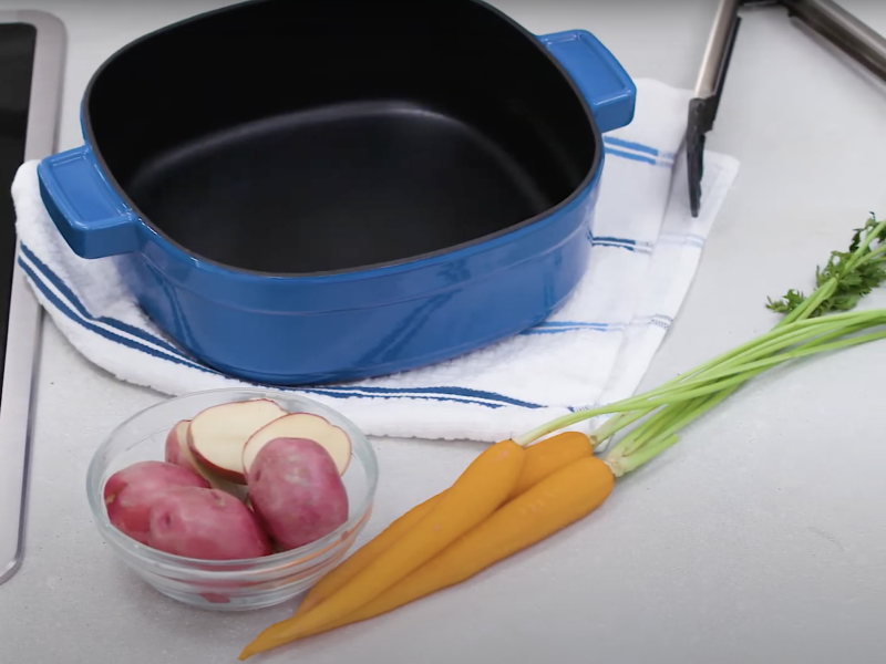 Blue dutch oven next to vegetables on a countertop