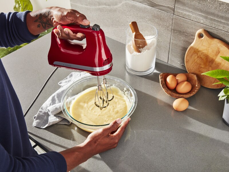 Person using KitchenAid® hand mixer over bowl of batter Person using KitchenAid® hand mixer over bowl of batter