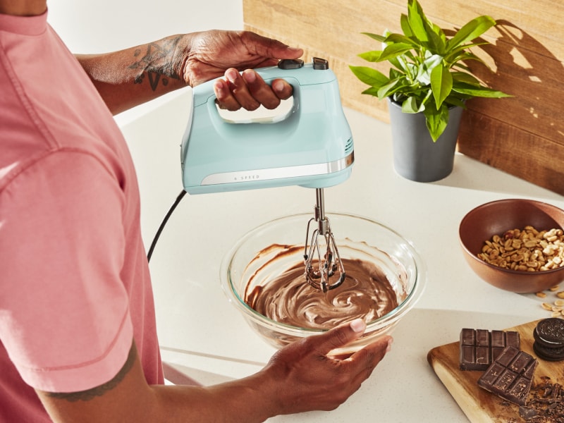 Person using KitchenAid® hand mixer over bowl of batter