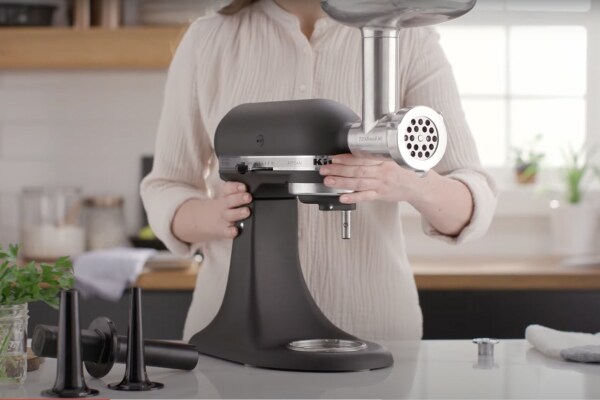 Person attaching the KitchenAid Metal Food Grinder attachment to the stand mixer