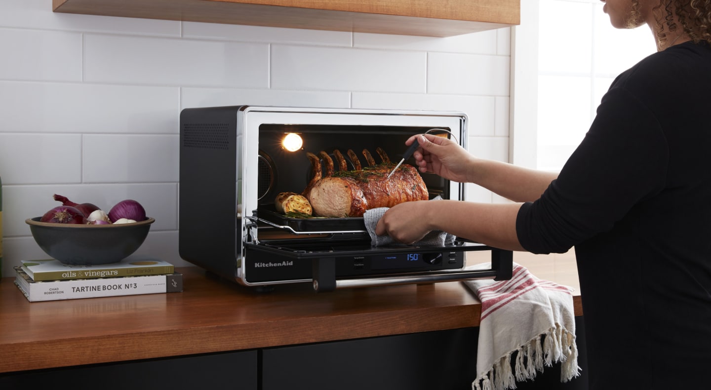A pork roast being removed from a KitchenAid® Countertop Oven A pork roast being removed from a KitchenAid® Countertop Oven