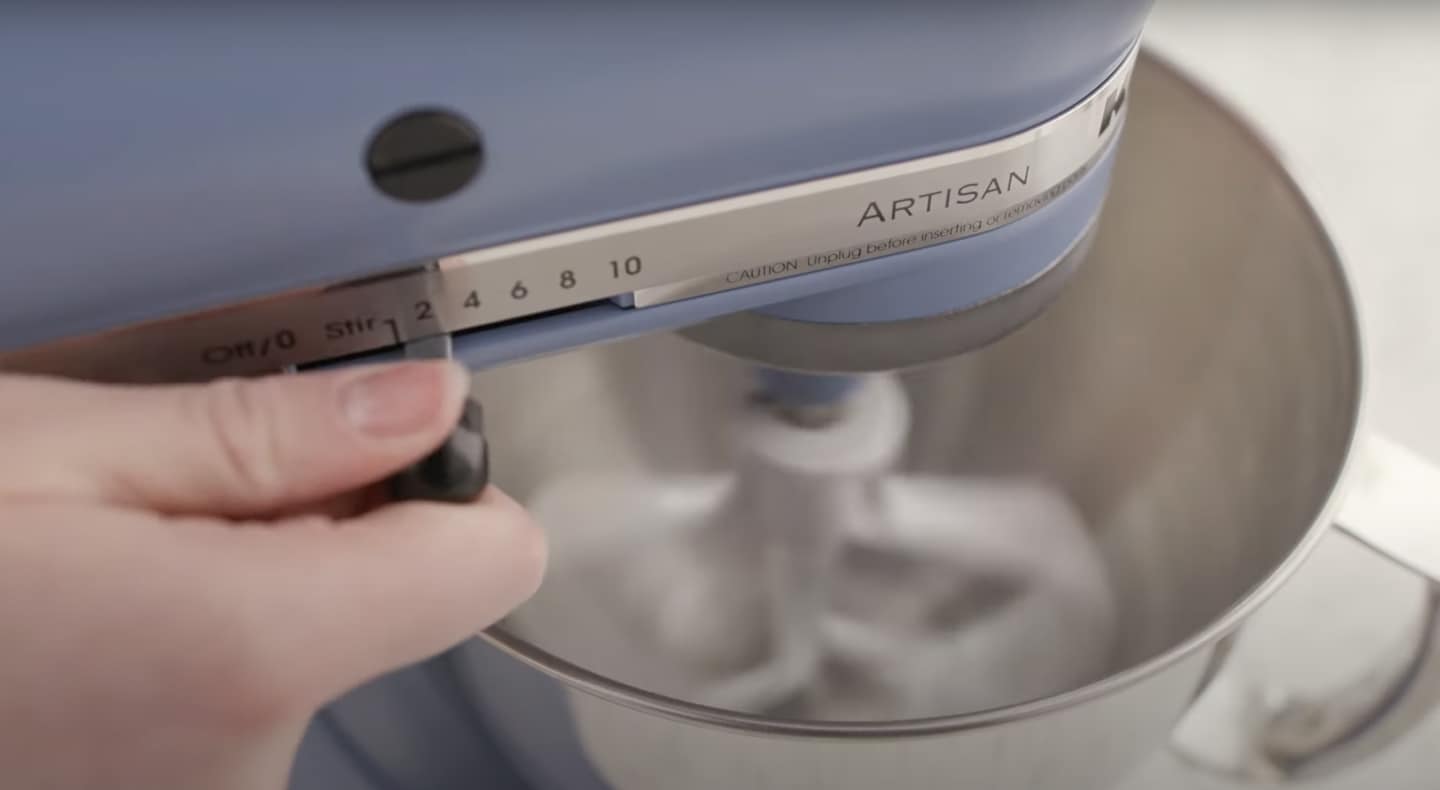 Person adjusting speed of blue KitchenAid® stand mixer Person adjusting speed of blue KitchenAid® stand mixer