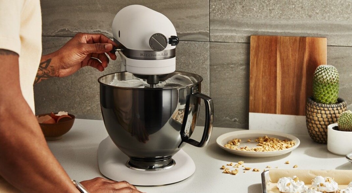 Person adjusting speed on white KitchenAid® stand mixer Person adjusting speed on white KitchenAid® stand mixer