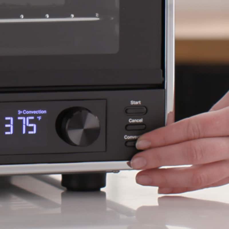 Close-up of person selecting air fryer settings.