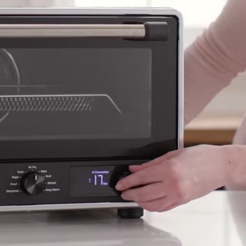 Close-up of person setting air fryer cooking time.