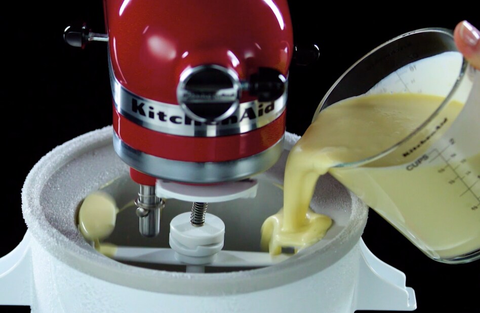Hand pouring homemade ice cream base into Ice Cream Maker attachment Hand pouring homemade ice cream base into Ice Cream Maker attachment