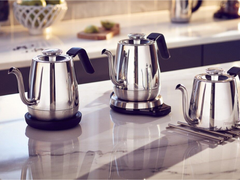 Three KitchenAid® electric tea kettles on the island next to cups of tea and cookie tray. Three KitchenAid® electric tea kettles on the island next to cups of tea and cookie tray.