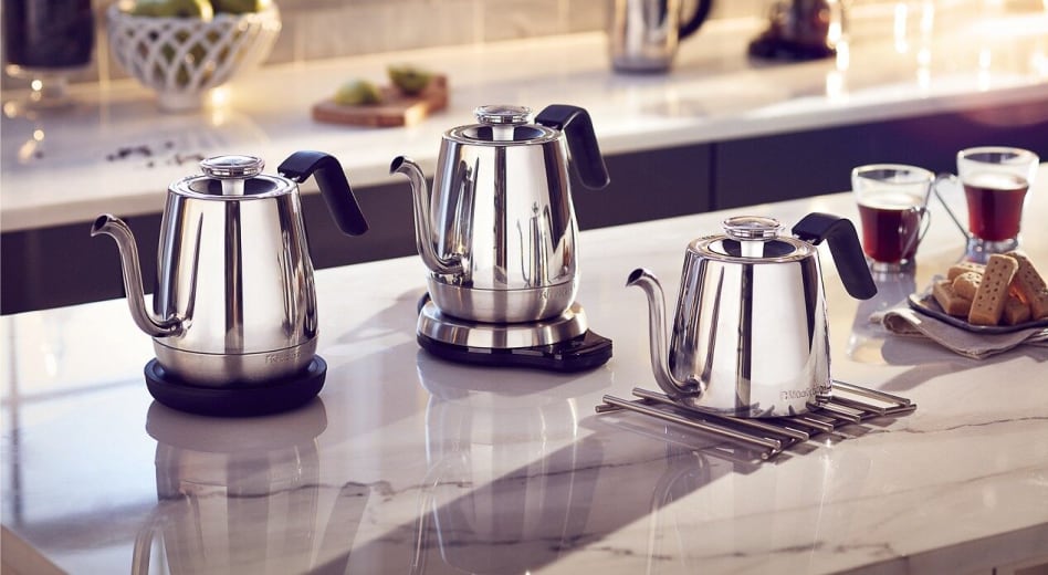Three KitchenAid® electric tea kettles on the island next to cups of tea and cookie tray. Three KitchenAid® electric tea kettles on the island next to cups of tea and cookie tray.